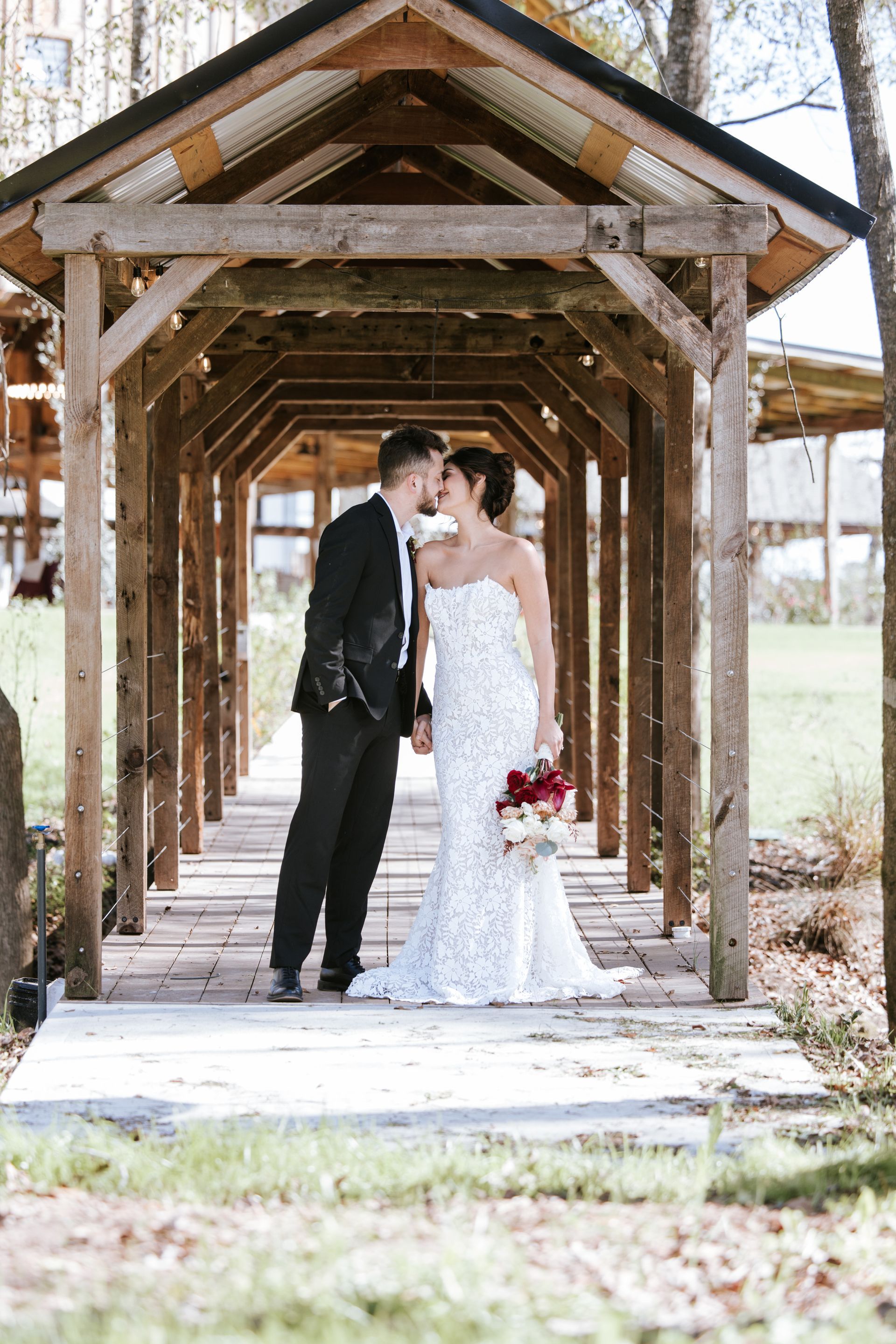 Bride and groom kissing under a rustic wooden gazebo outdoors