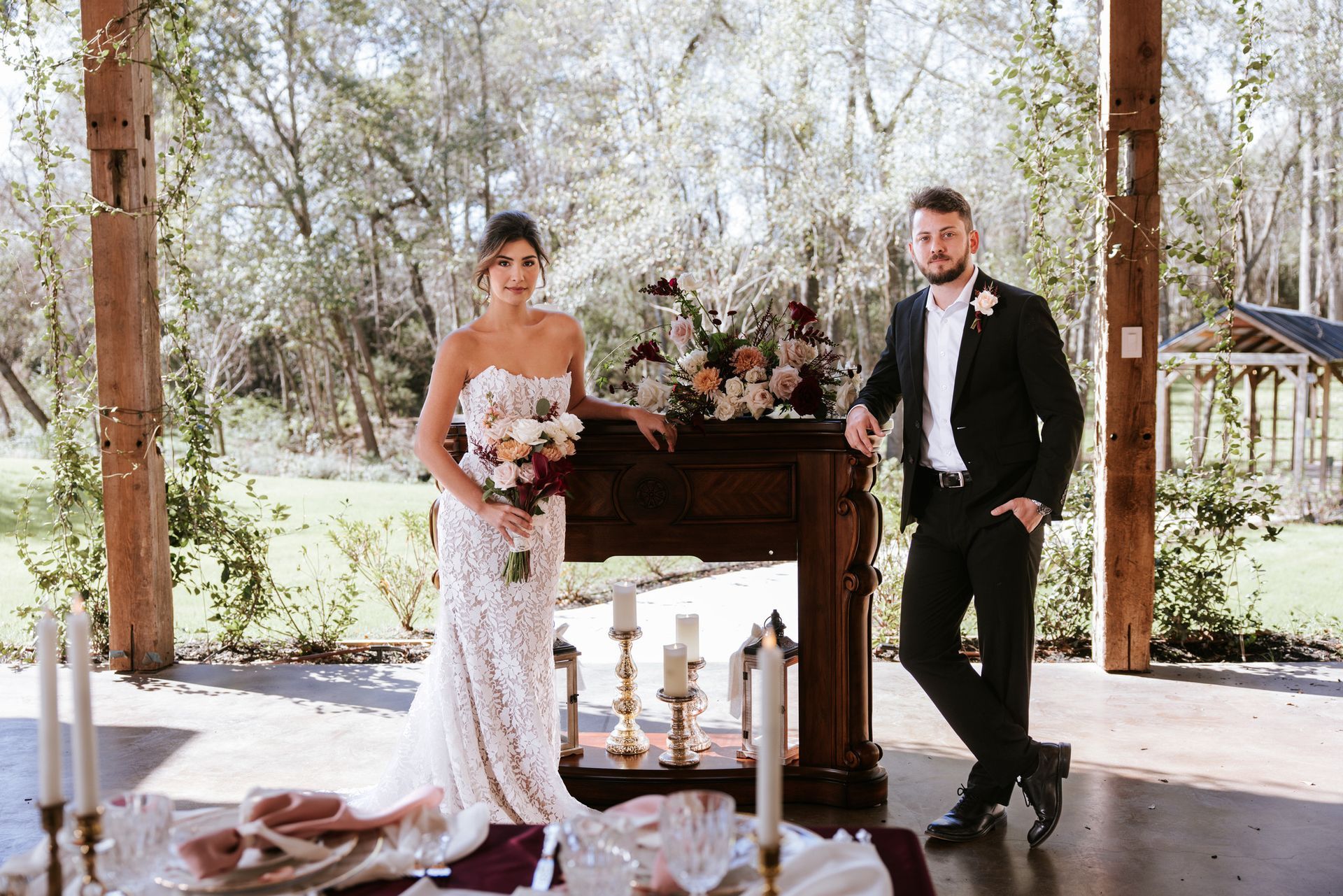 Bride and groom standing beside a floral-decorated altar at an outdoor wedding ceremony