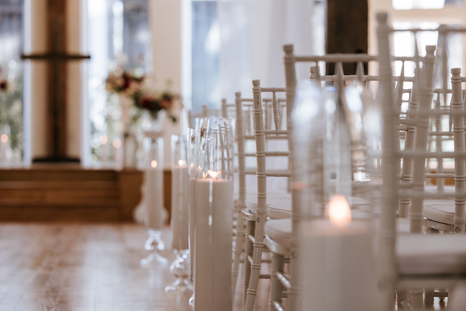 Rows of white chairs and glass candles in a softly lit wedding ceremony venue