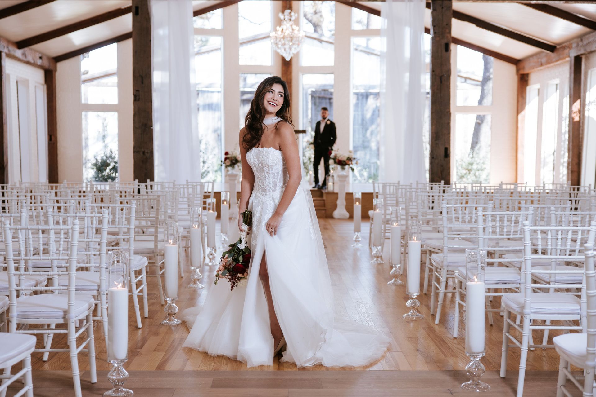 Bride in white gown standing in a bright wedding chapel with rows of white chairs