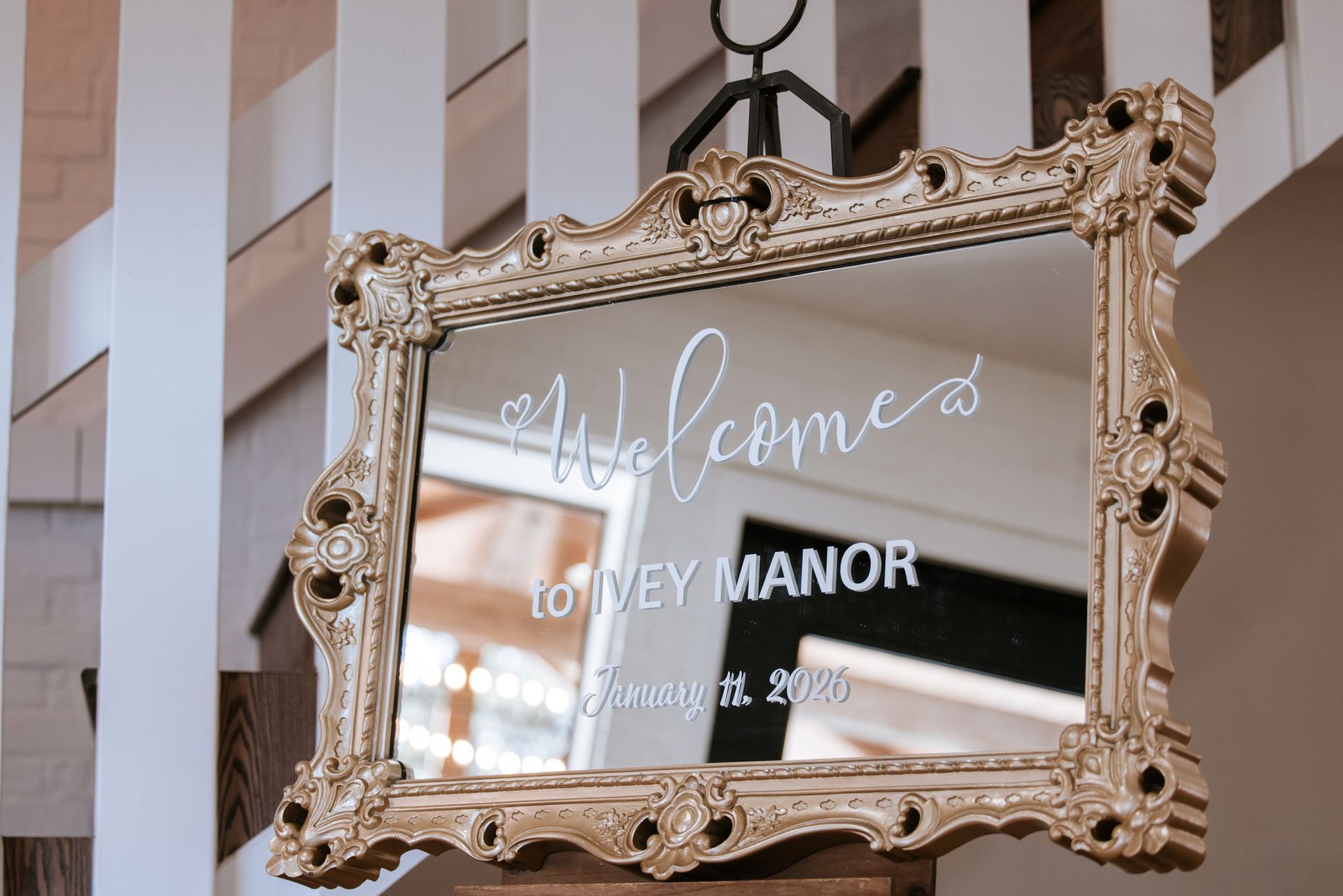 Ornate gold-framed mirror sign reading “Welcome to Ivy Manor” hanging indoors