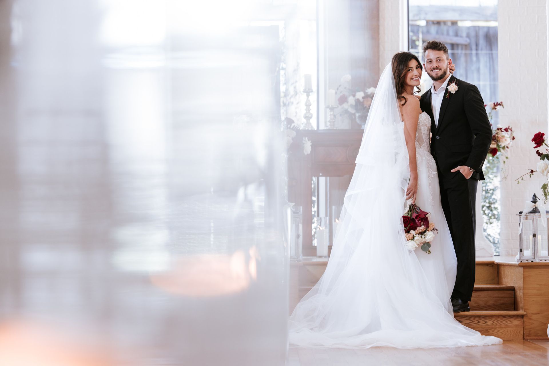 Bride and groom standing together at a wedding ceremony, bride in white gown with bouquet, groom in black tuxedo
