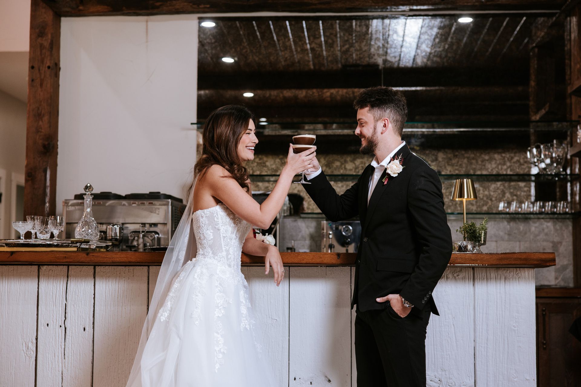 Bride and groomasting wine at a rustic indoor reception bar