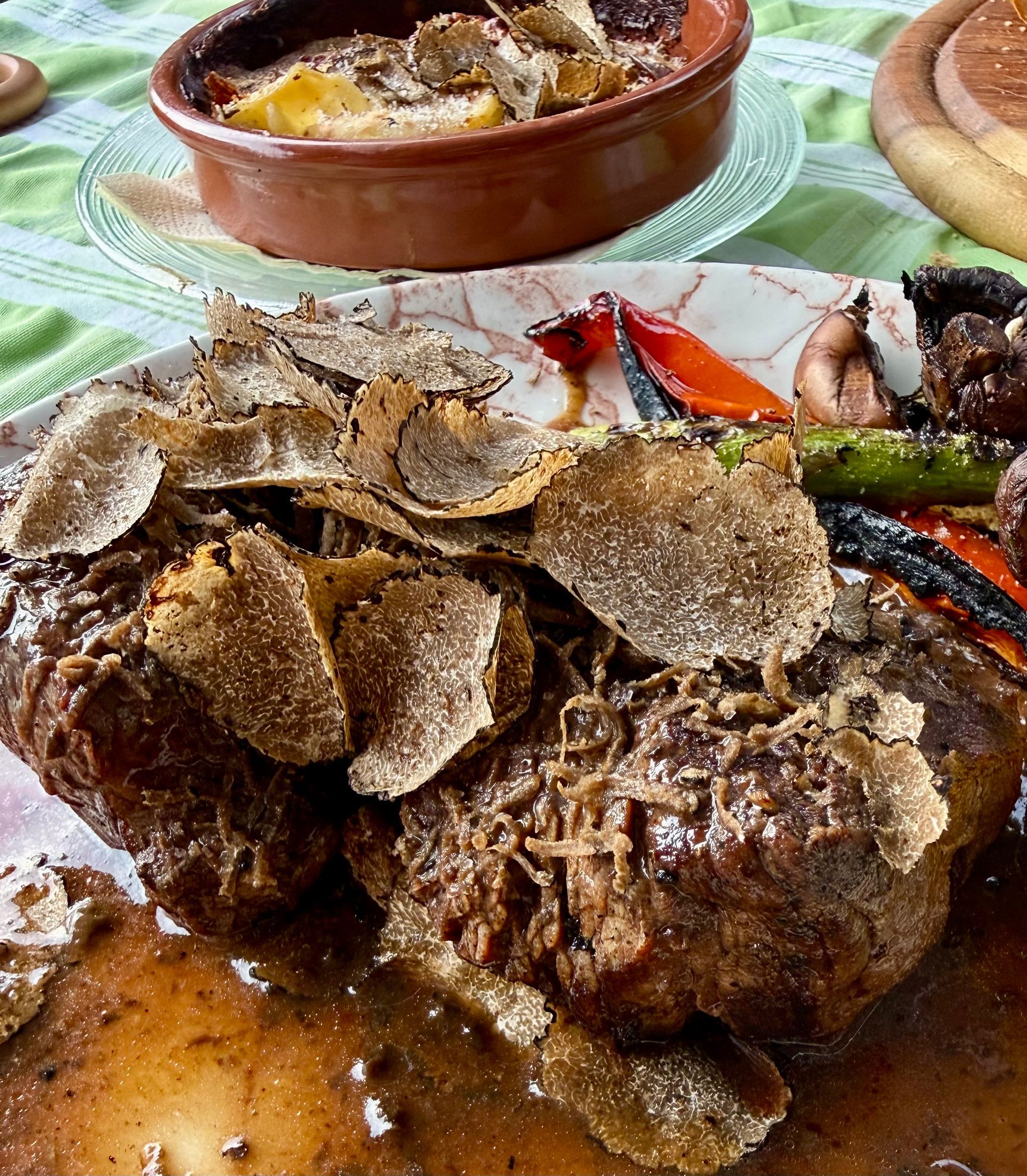 Close-up of truffle-covered meat on a plate, with a brown bowl in the background at Gold Istra, Slovenia