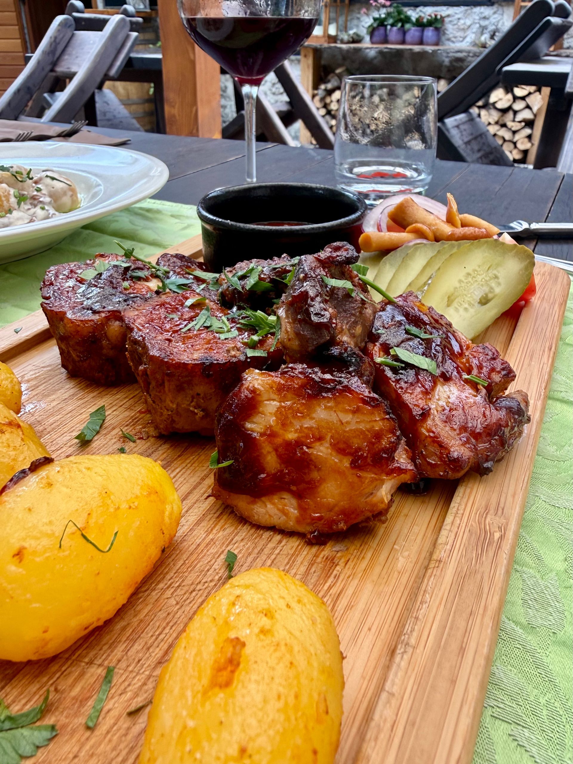 BBQ Pork Ribs dinner with vegetables and potatoes on a wooden board at an outdoor table at Pristava Lepena in Slovenia