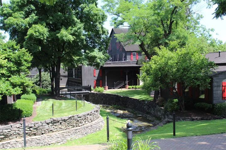large house surrounded by trees and a stone wall.