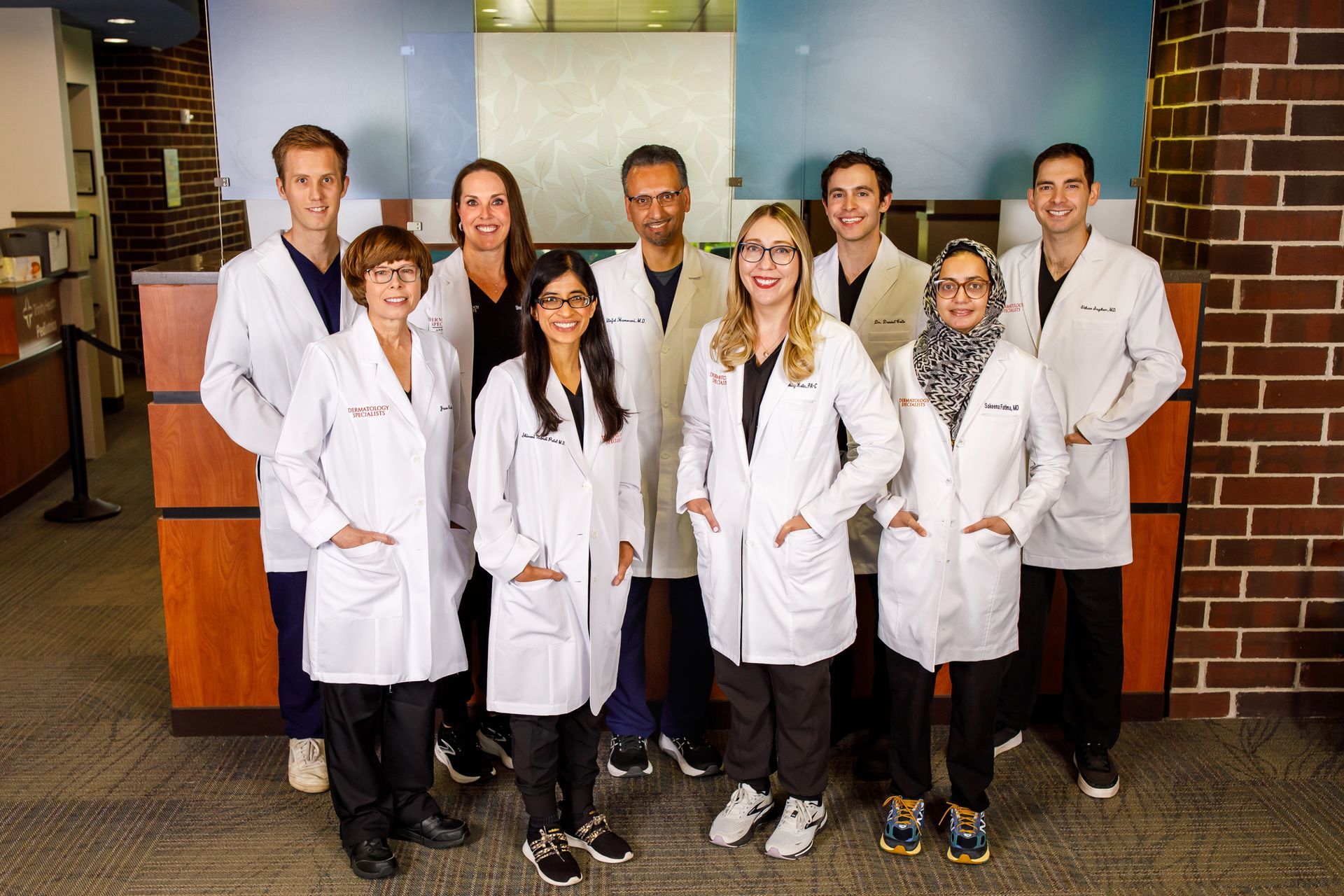 Group of medical professionals, dressed in white coats, posing in a medical office setting.