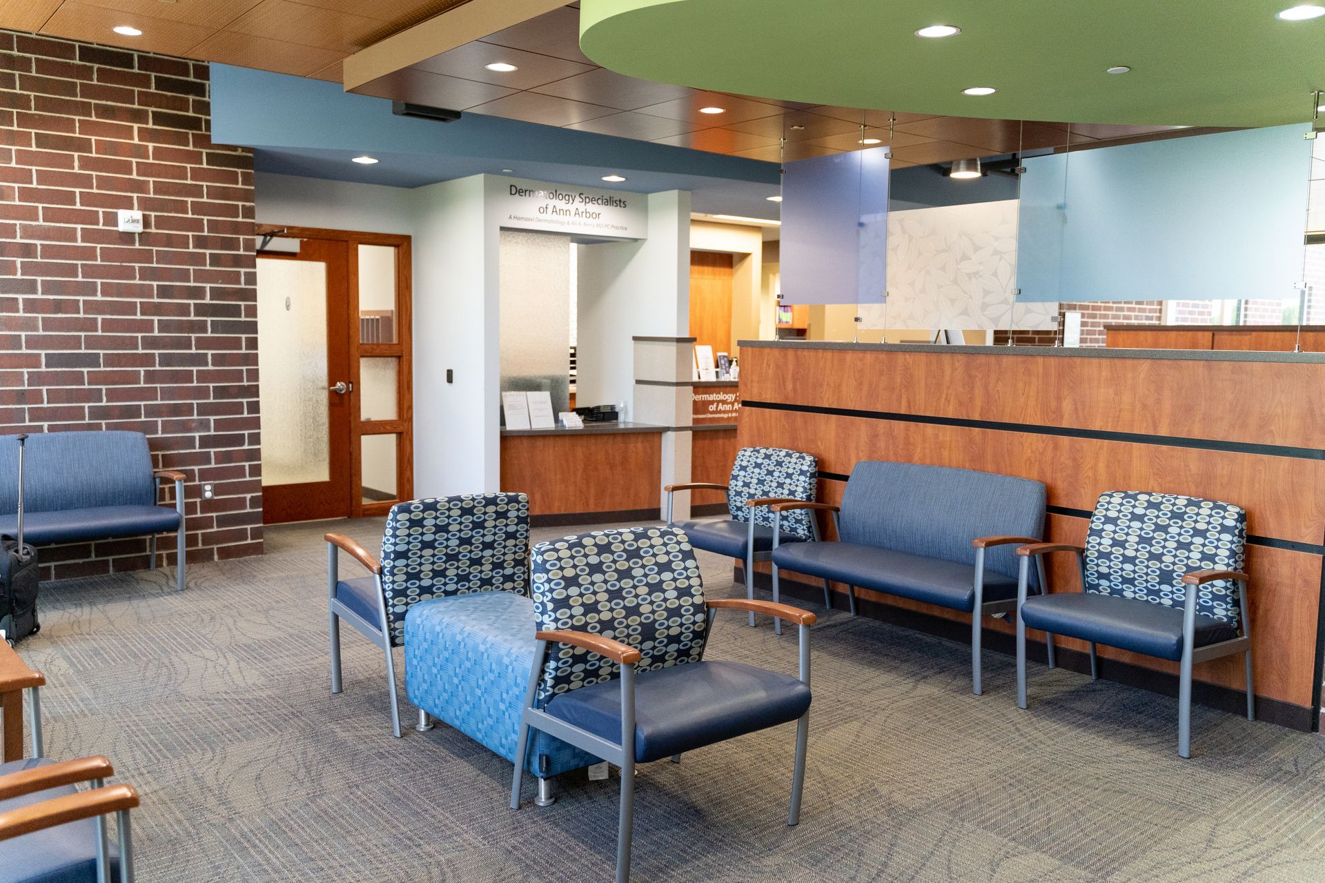 Waiting room with blue seating, brick wall, and wooden reception desk.