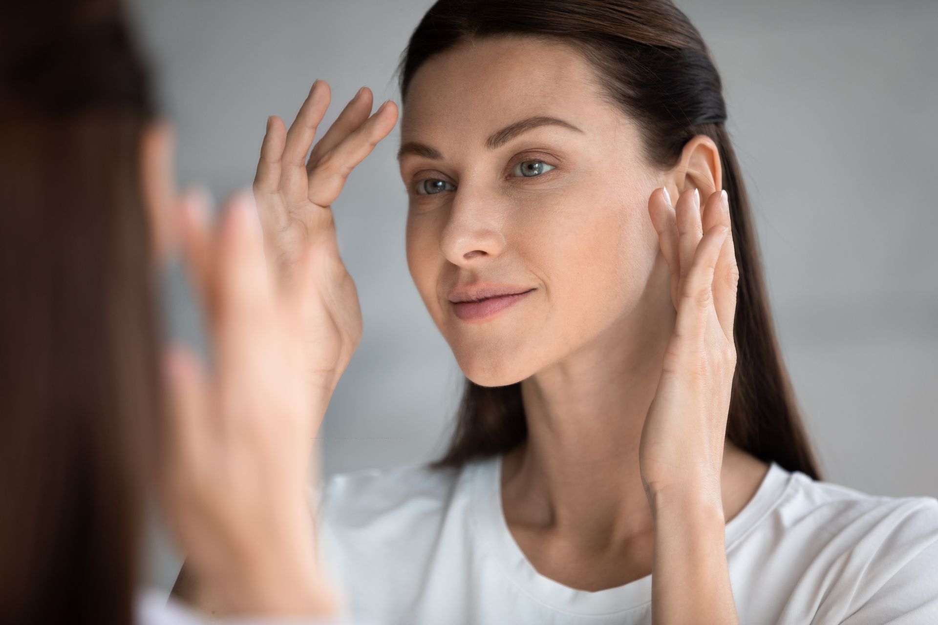 Close-up of a beautiful woman with perfect skin looking in a mirror.