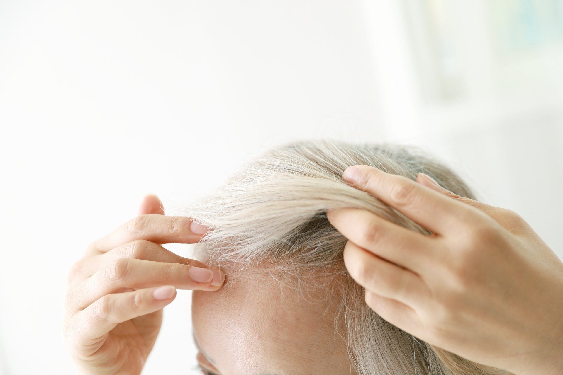 Person examining their graying hair.