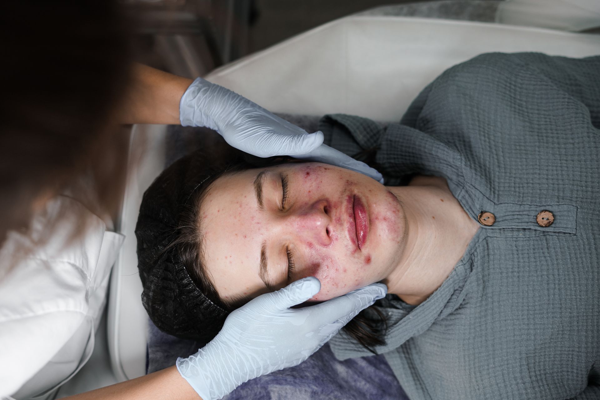 A woman is enjoying a facial treatment in a salon, highlighting acne dermatology treatment.