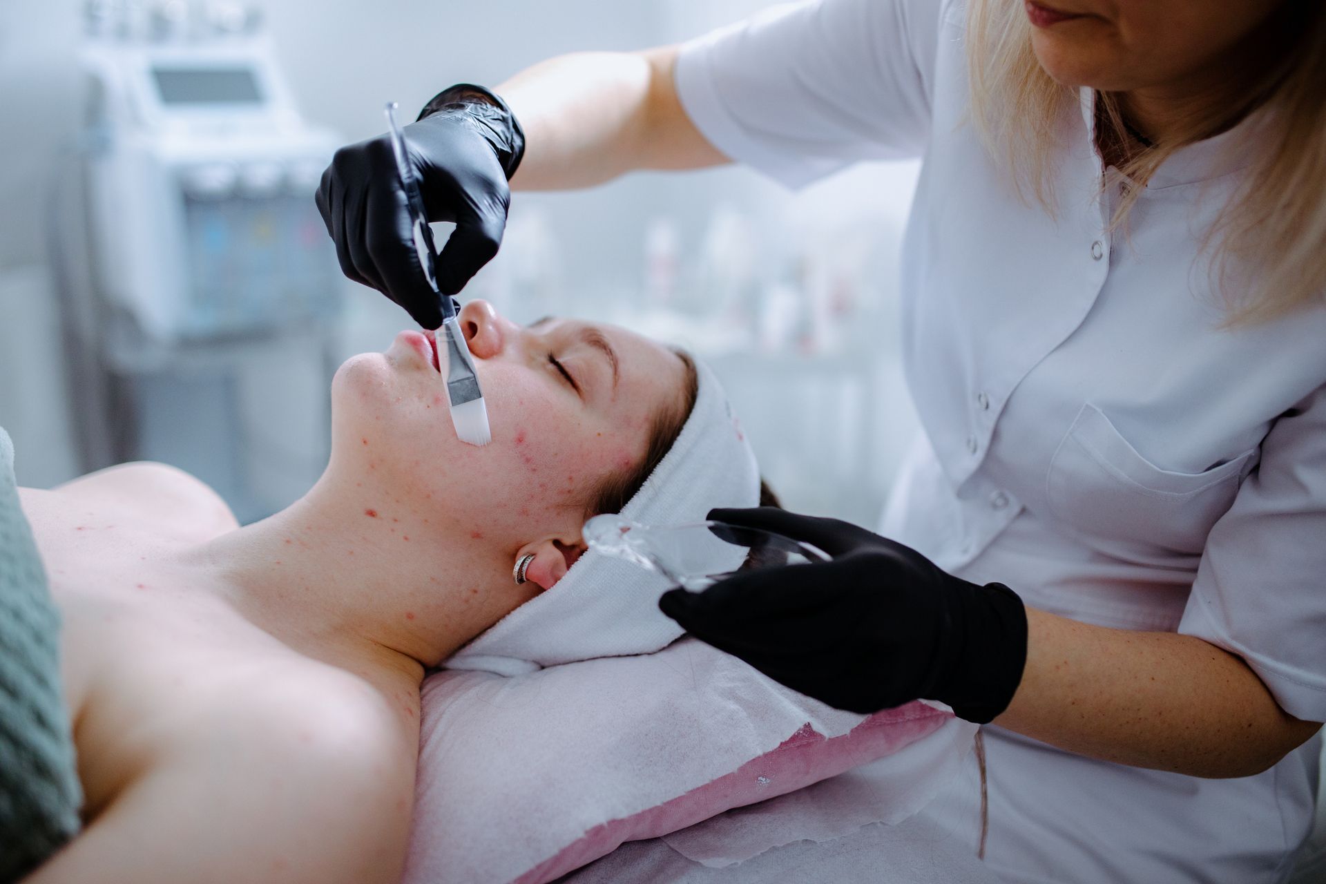 A woman receiving an acne facial treatment at a beauty salon for an improved complexion.