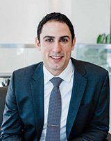 a man in a suit and tie is smiling for the camera . | Local Specialists in Shelby Twp., MI | Hamzavi Dermatology