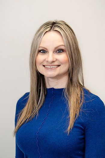 Woman with blonde hair, wearing a blue sweater, smiling at the camera.
