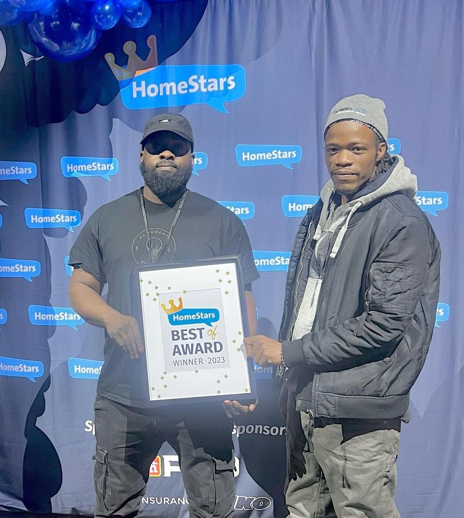 Two men pose at a HomeStars event, holding a Best Award plaque in front of a branded backdrop.
