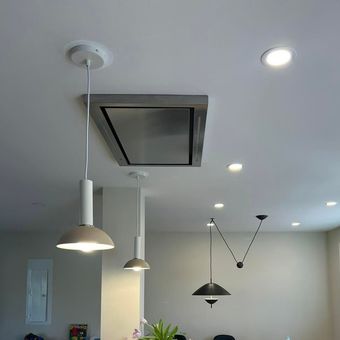 White ceiling with recessed lights, pendant lamps, and a square attic vent in a modern room