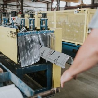 Worker guides sheet metal through an industrial machine in a factory