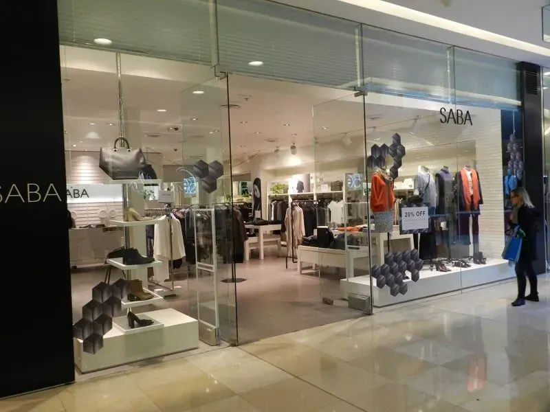 A Woman Is Standing In Front Of A Clothing Store In A Mall — Avoca Beach Glass In West Gosford, NSW