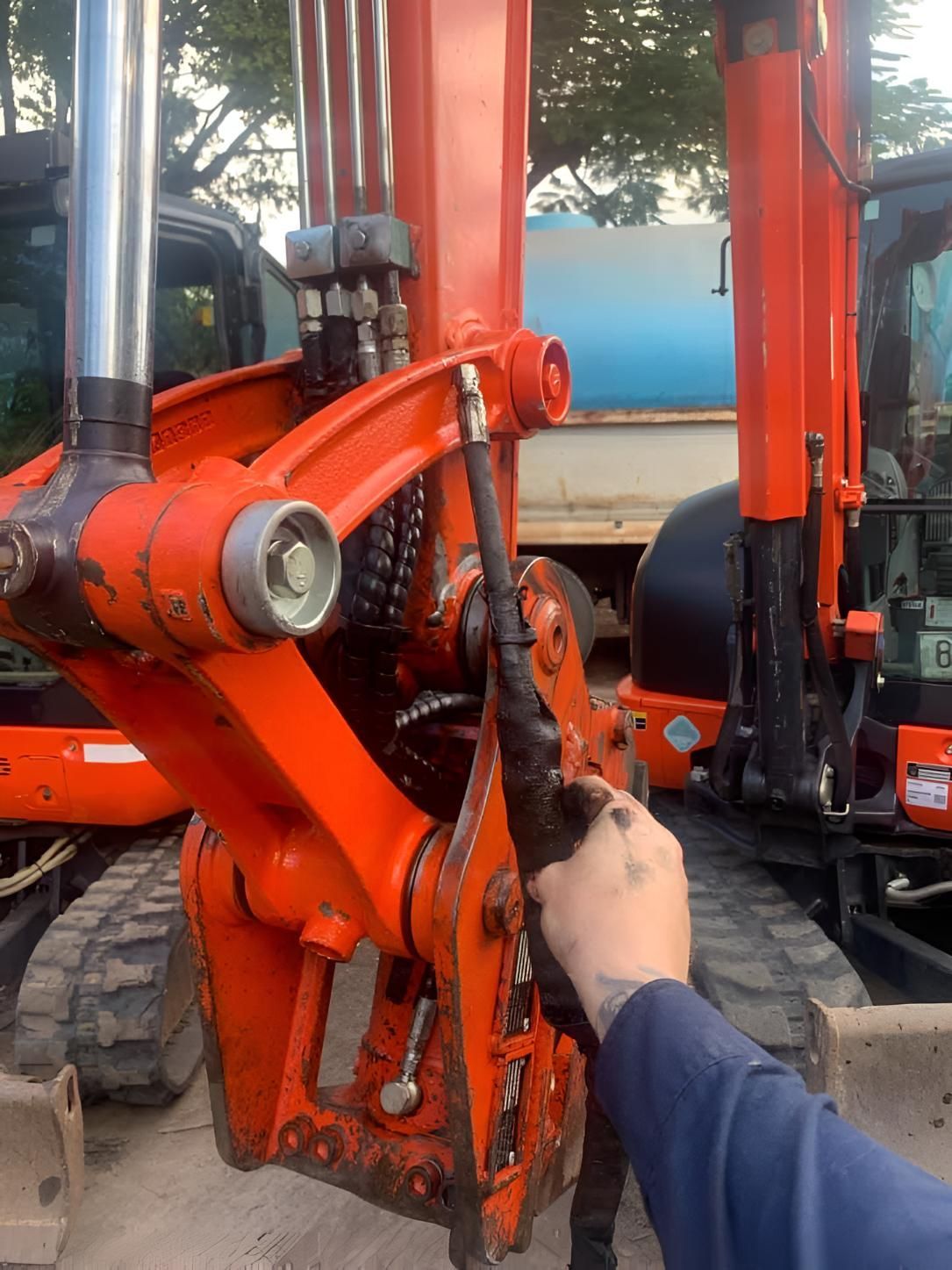 A Person Is Working On An Orange Excavator With A Hose Attached To It — Mackay Hose Fitting Services In West Mackay, QLD