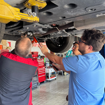 Mechanic  working on a car with the hood open in a garage. | Premier Auto Service Center