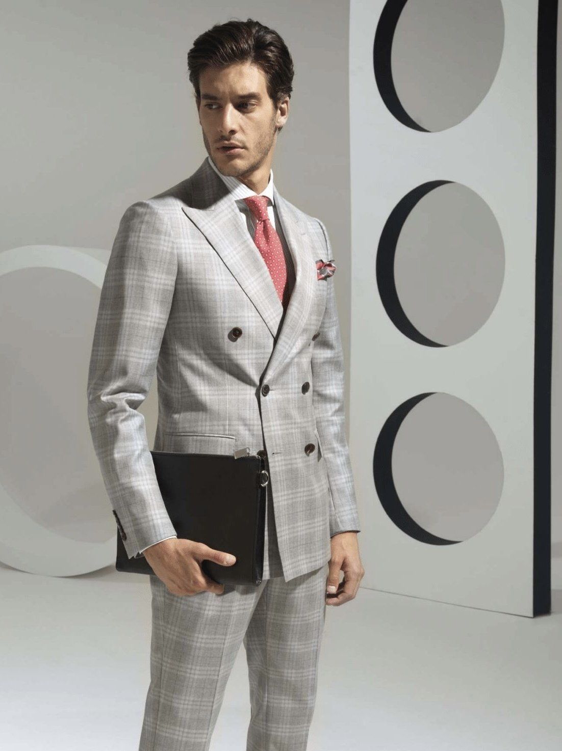 A man in a suit and tie is holding a black briefcase.