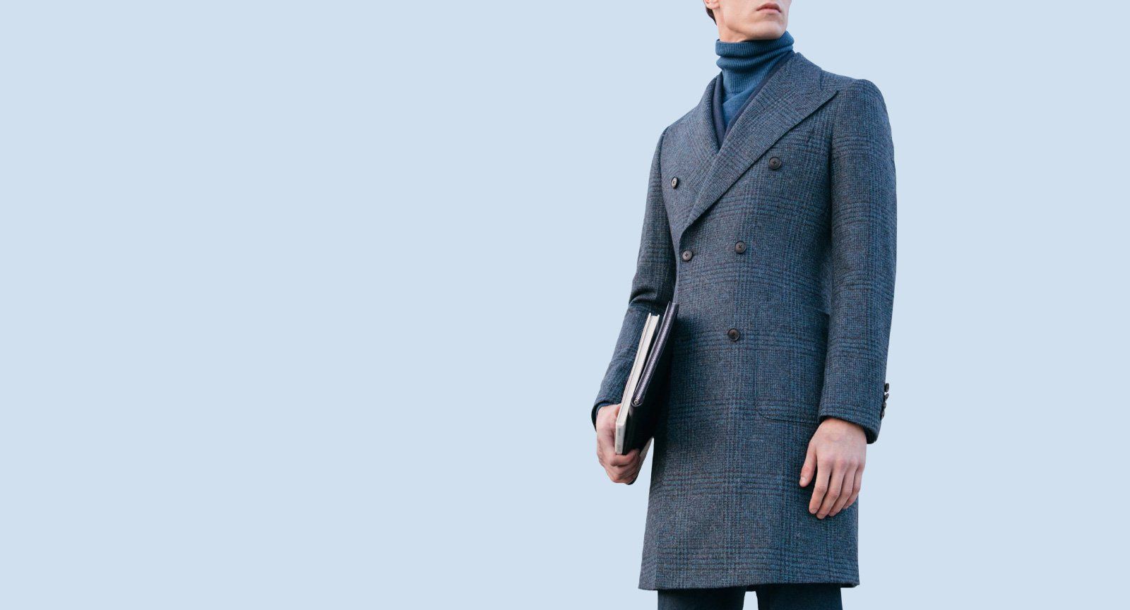 A man in a grey coat is holding a briefcase.