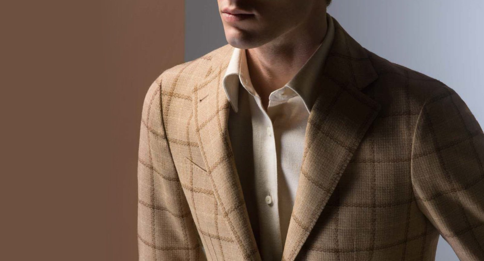 A man is wearing a tan suit jacket and a white shirt.