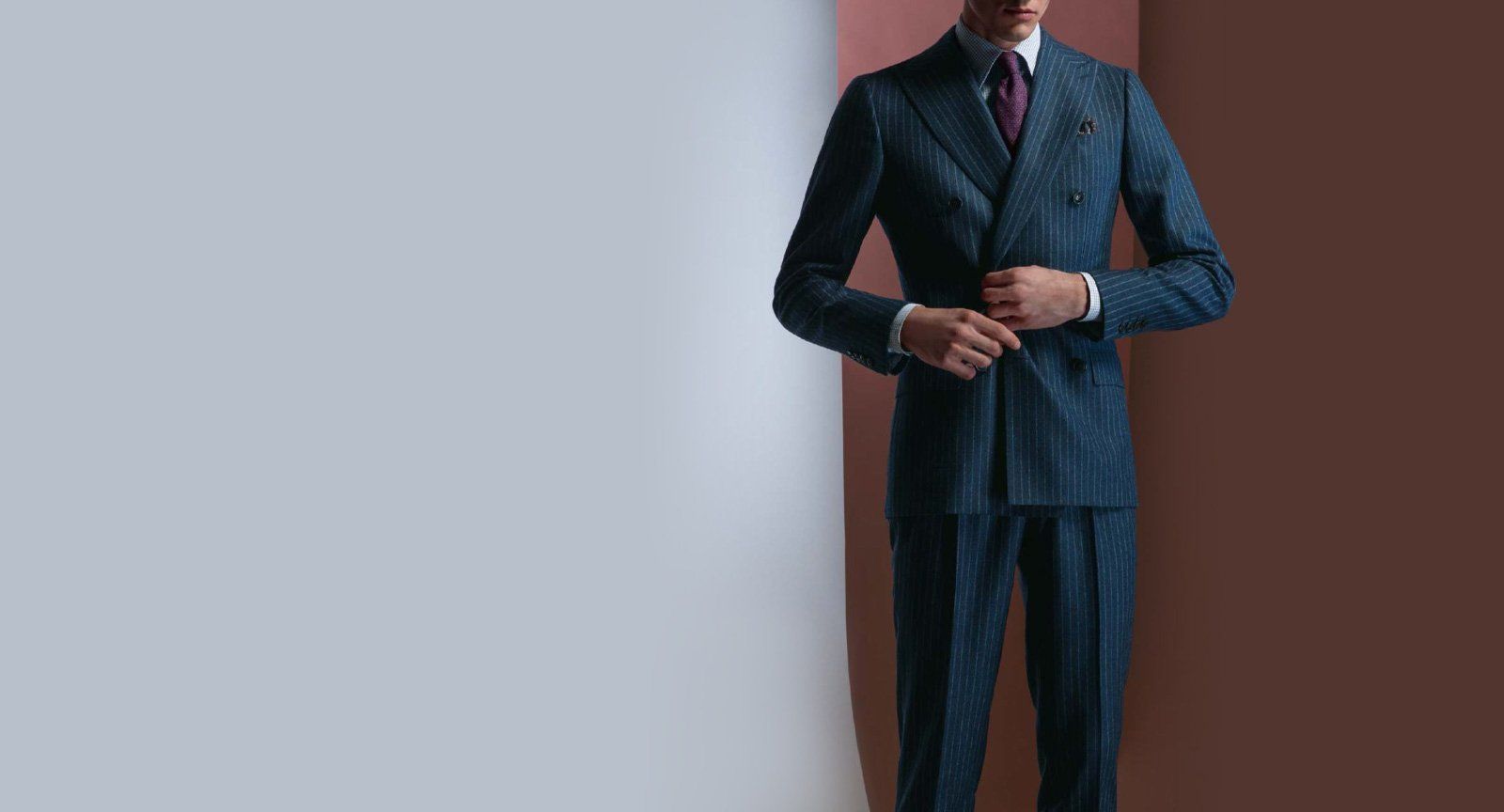 A man in a suit and tie is standing in front of a wall.