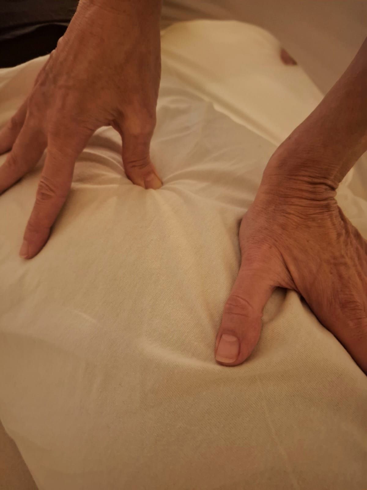 Mani premute su un telo bianco da massaggio, probabilmente durante una seduta di massaggio.