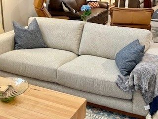 Beige Sofa With Blue Pillows and Blanket — Hastings Specialty Furniture In Port Macquarie, NSW