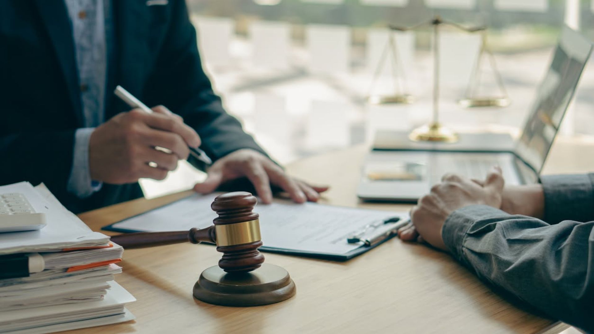 Lawyer and client discussing documents at a desk with a gavel in the foreground