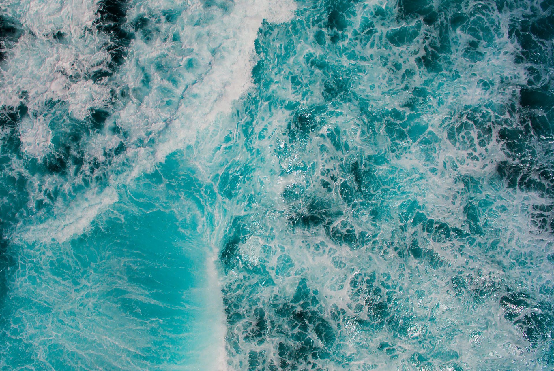 Foaming turquoise ocean water, waves crashing.