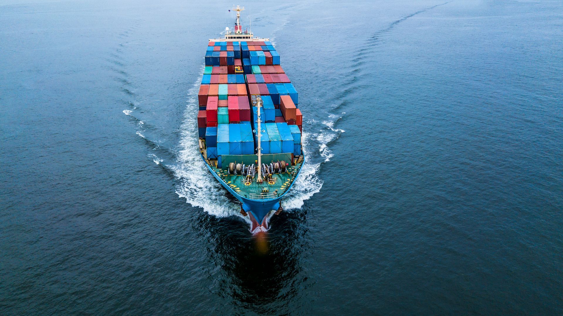 Cargo ship sailing on blue water, carrying colorful containers.