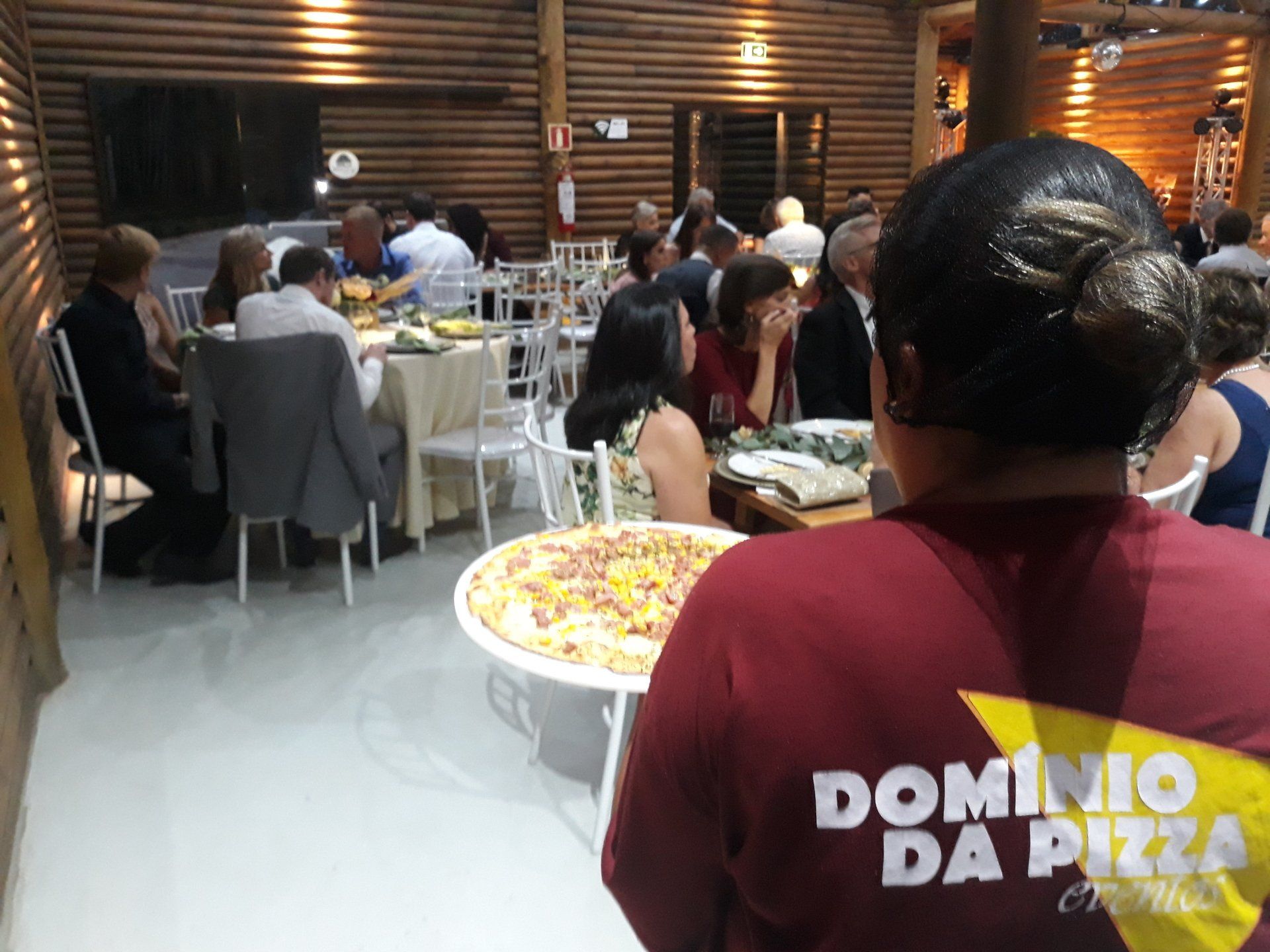Buffet de banquete com pessoas sentadas em mesas em uma sala de jantar rústica de madeira.