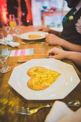 Mesa de jantar com um prato branco de omelete e a mão de uma pessoa ao lado, em um restaurante.
