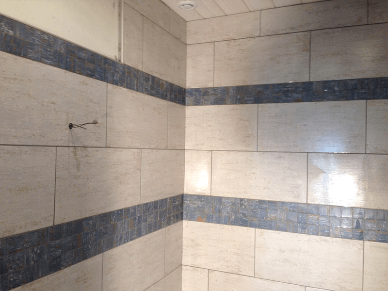 Une salle de bain avec carrelage blanc et rayures bleues sur les murs