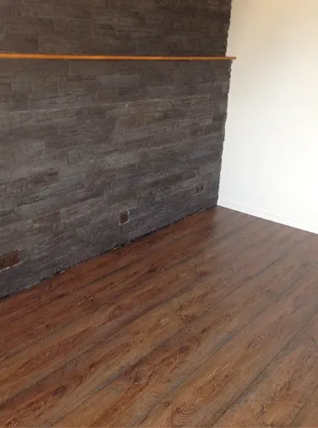 Une pièce avec un parquet et un mur de briques.