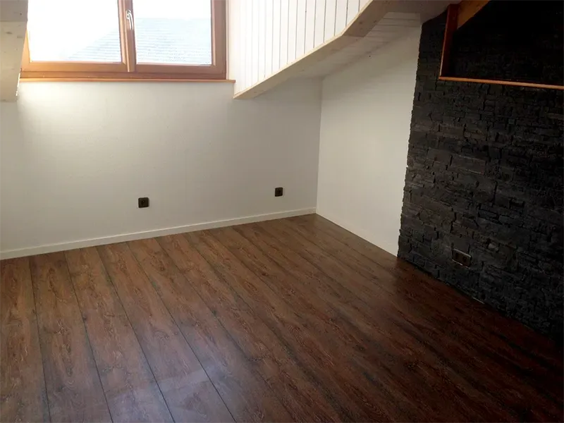 Une pièce avec un parquet et une fenêtre.