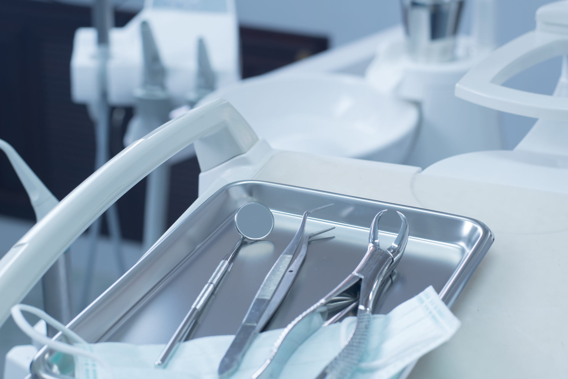 Instrumental dental en una bandeja metálica junto a un sillón dental