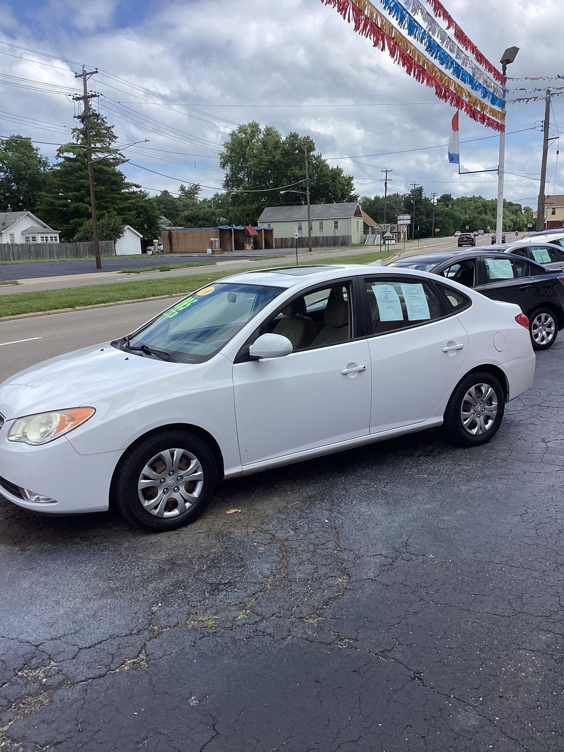 Silver sedan parked on a wet lot in front of a white building