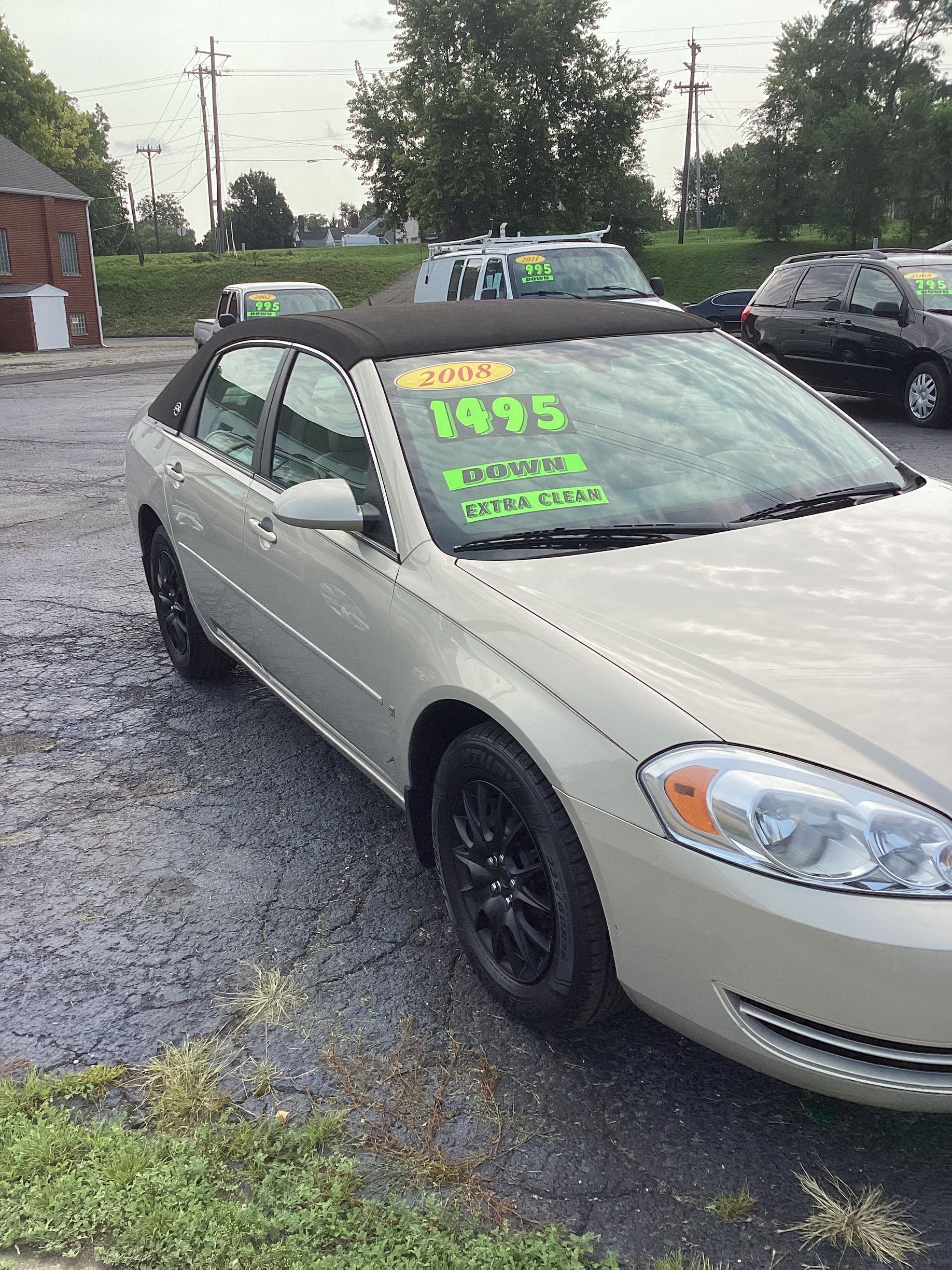 Black sedan parked by Bill Williams Auto Sales with price written on the windshield.