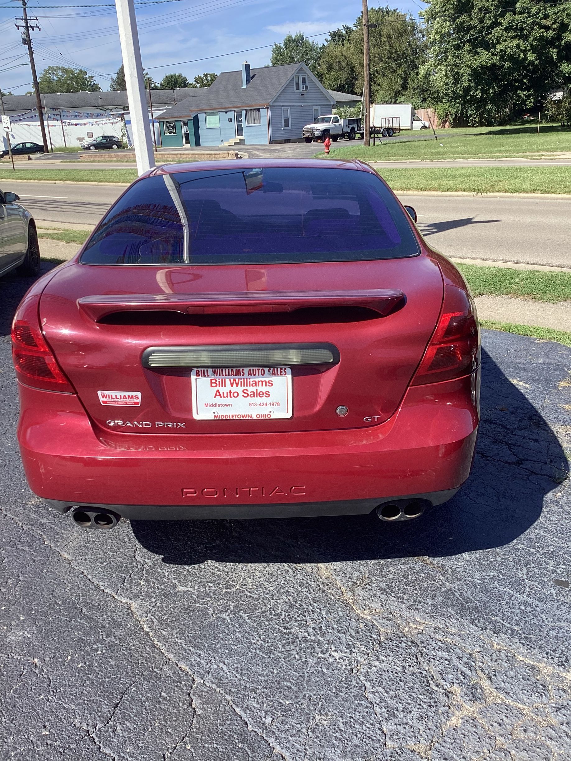 Black sedan parked by Bill Williams Auto Sales with price written on the windshield.