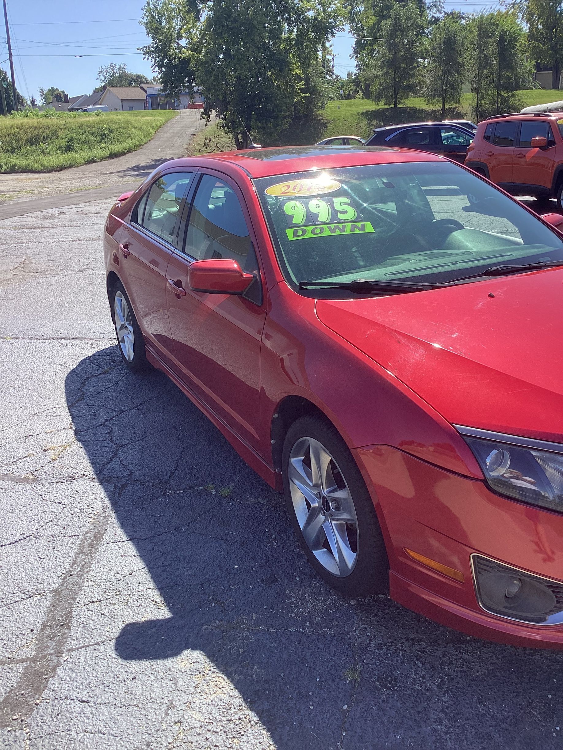 Black sedan parked by Bill Williams Auto Sales with price written on the windshield.