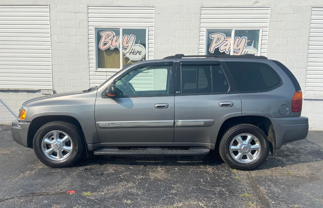 Gray SUV parked beside a white building with windows and flower boxes.