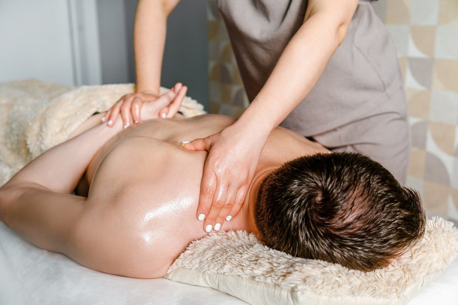 Massage therapist giving a back massage to a client lying face down on a towel-covered table