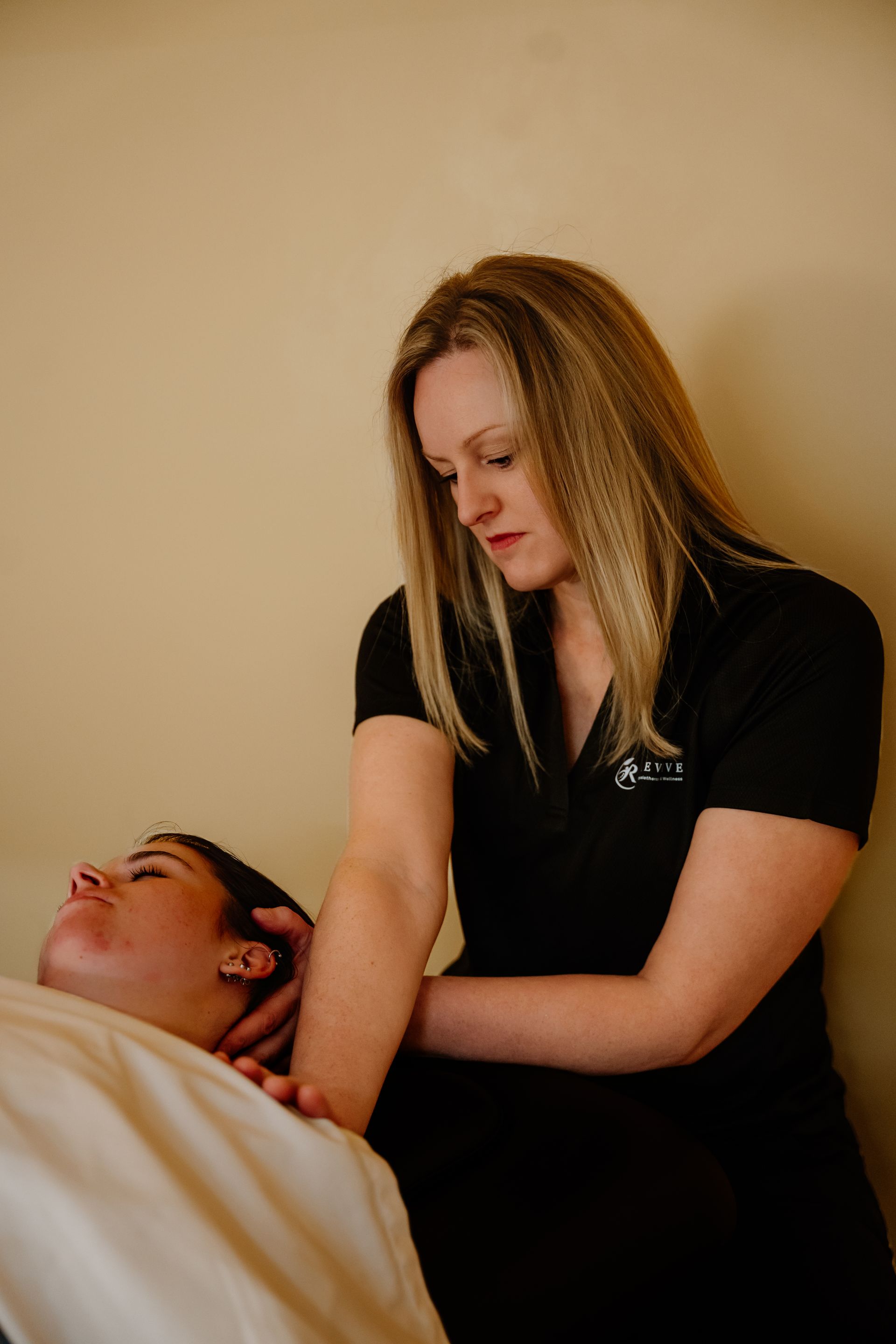 Hands massaging a person’s calf and foot on a white towel, spa setting