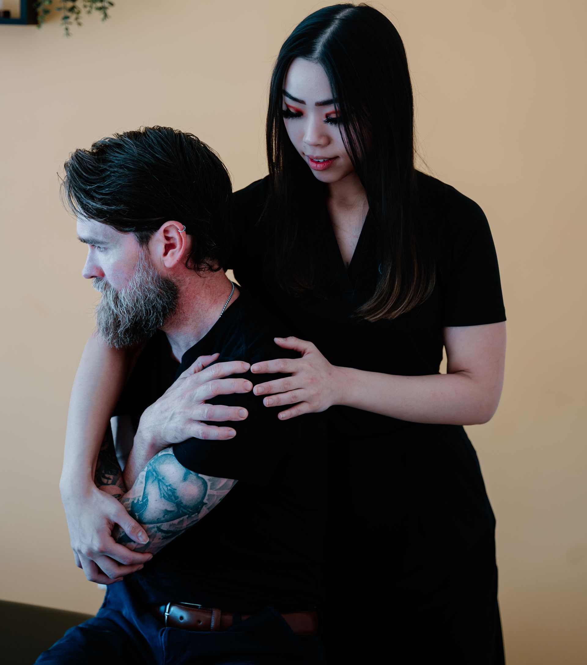 Physical therapist helping an older patient stretch his shoulder in a bright clinic room
