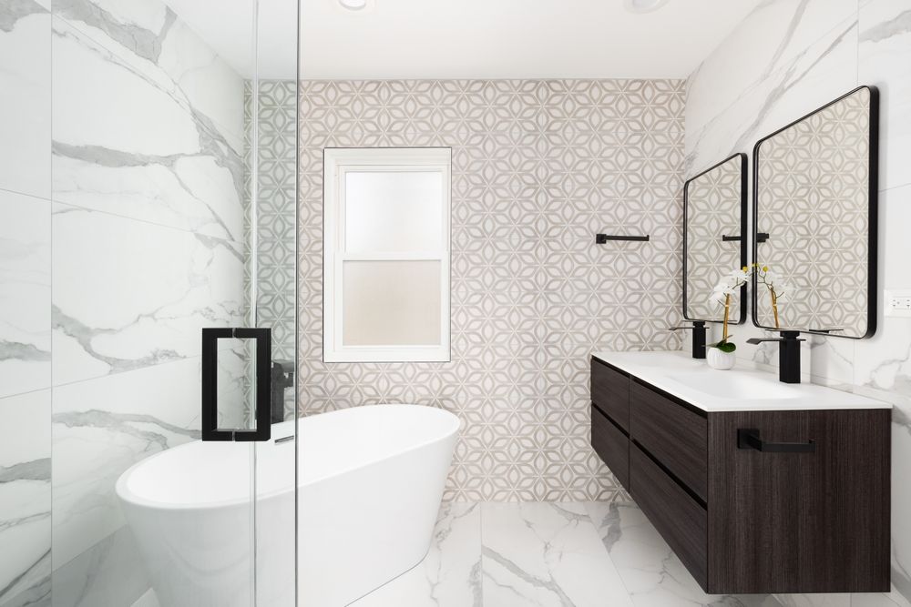 Modern bathroom with marble walls, freestanding tub, and floating dark wood vanity with black fixtures.