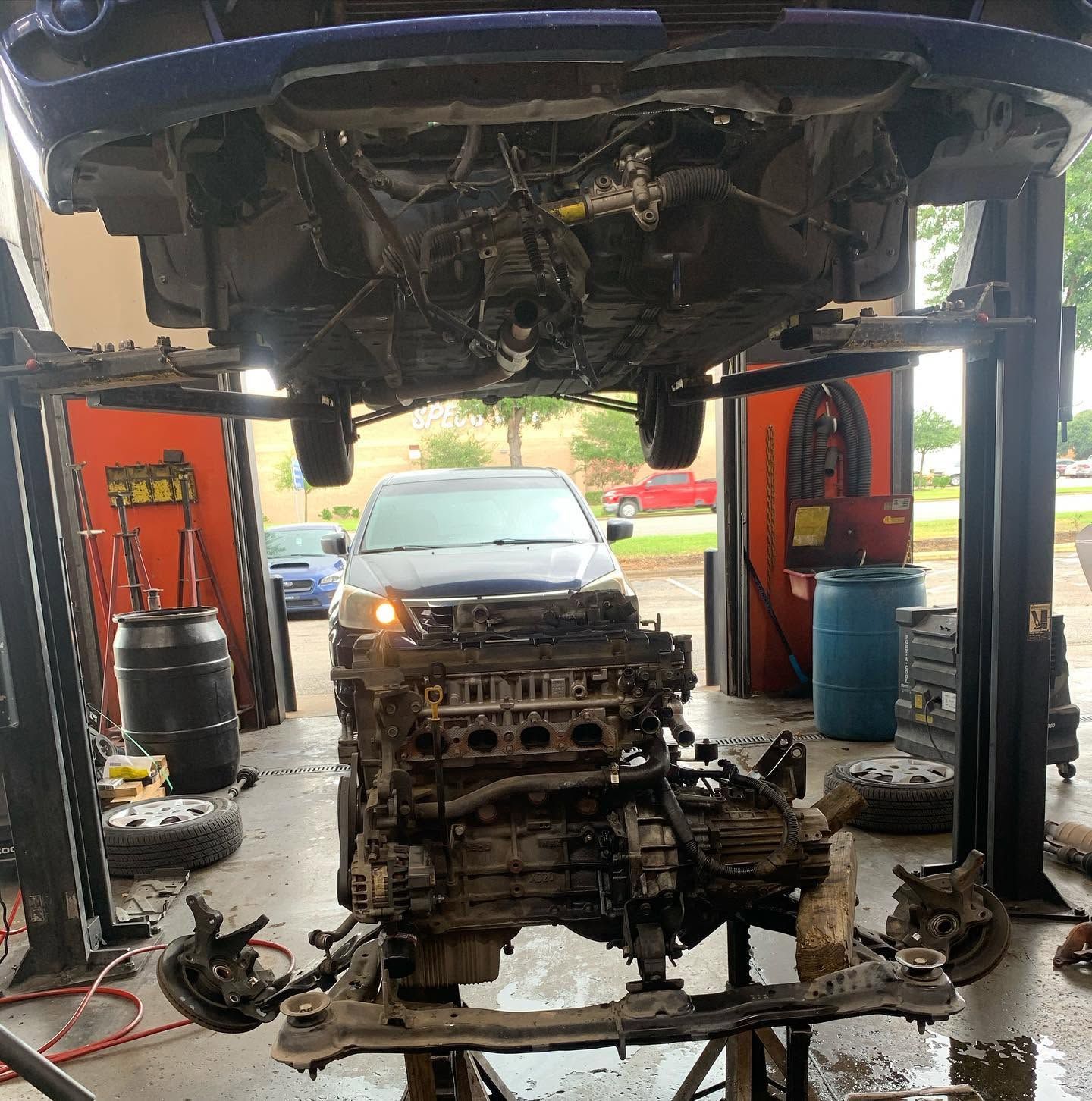 Vehicle Raised On Lift With Removed Engine Assembly In Repair Bay | CarDoc Automotive