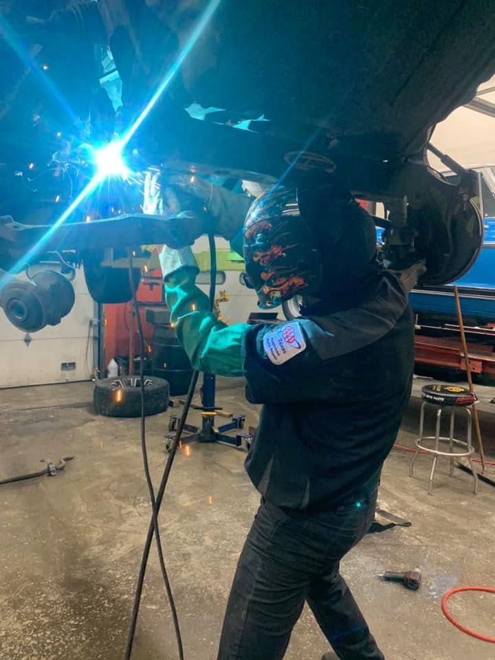 Automotive Technician Welding Beneath Vehicle Raised On Lift | CarDoc Automotive